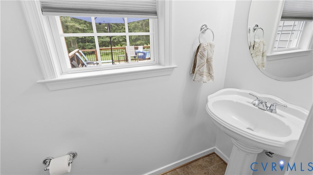 1836 Rocky Ford Road, Powhatan, VA 23139 White pedestal sink with chrome faucet, circular mirror, and window with wood trim