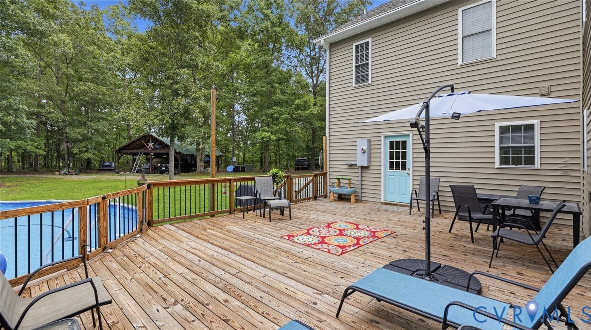 1836 Rocky Ford Road, Powhatan, VA 23139 Expansive custom wood deck with a built-in pool, wood railing, and a light blue exterior door
