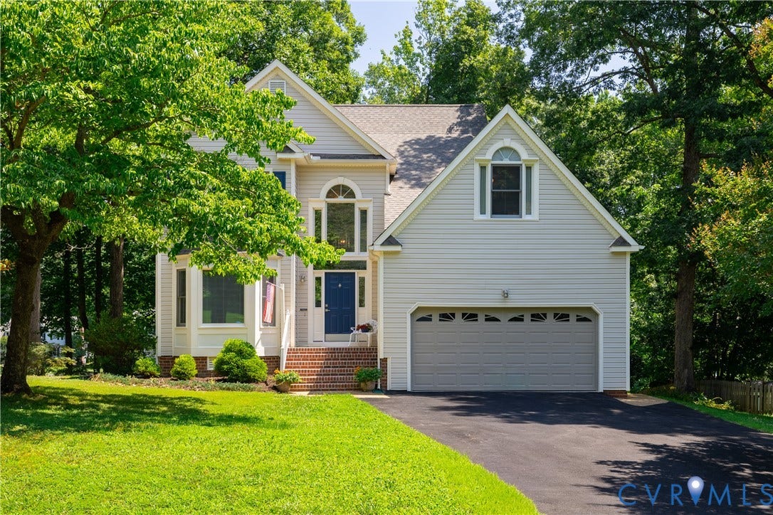 Two-story residence featuring light gray siding, an attached two-car garage, and a dark blue front door