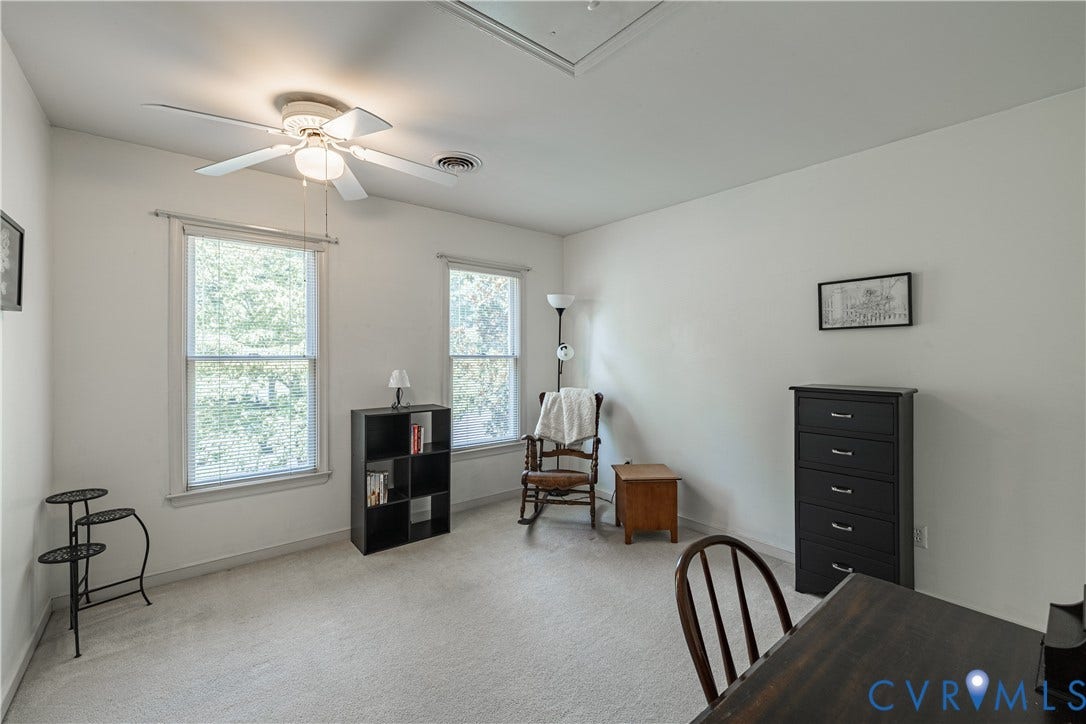 Carpeted room featuring a ceiling fan with integrated lighting, two windows with white trim, and a white ceiling