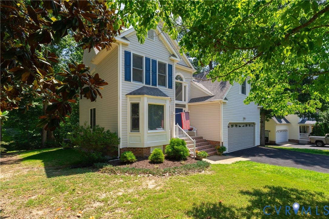 Traditional two-story residence featuring light-colored siding, a prominent bay window, and a two-car garage