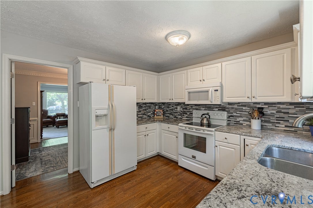Kitchen featuring white cabinetry, a mosaic tile backsplash, granite countertops, wood-finish flooring, and a ceiling-mounted light fixture