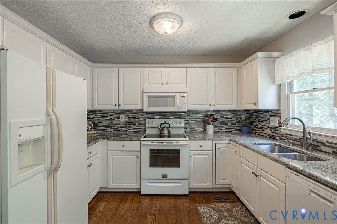 Kitchen featuring white cabinetry, granite-finish countertops, and a mosaic tile backsplash