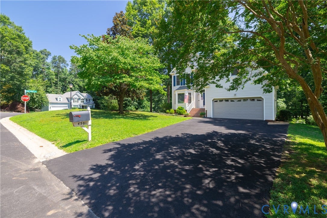 Traditional two-story home featuring a white siding exterior, an attached two-car garage, and a paved driveway