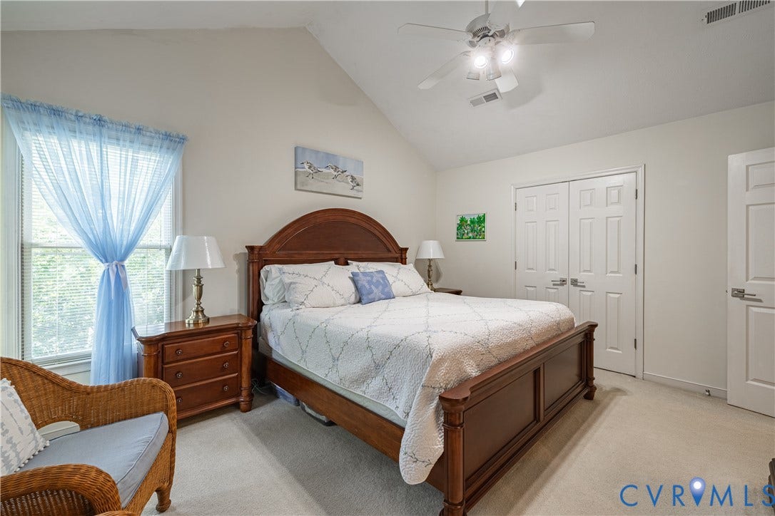 Vaulted ceiling bedroom featuring plush carpeting, a ceiling fan with integrated lighting, and a window with blinds