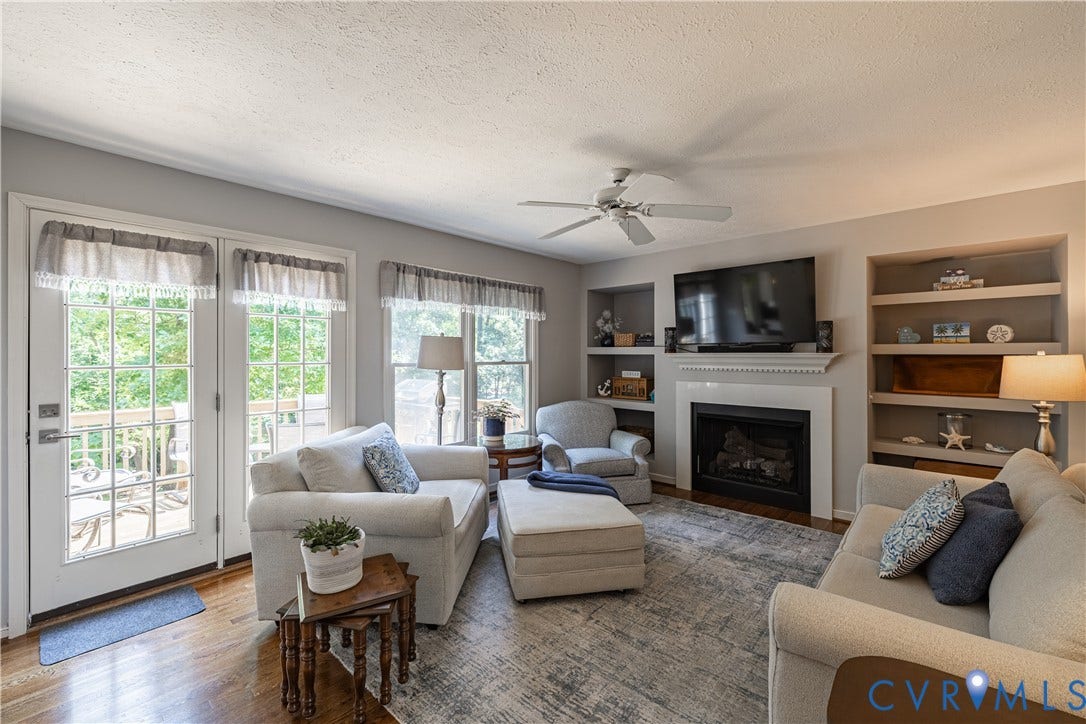 Living area featuring wood-finish flooring, a fireplace with a white mantel, and built-in shelving