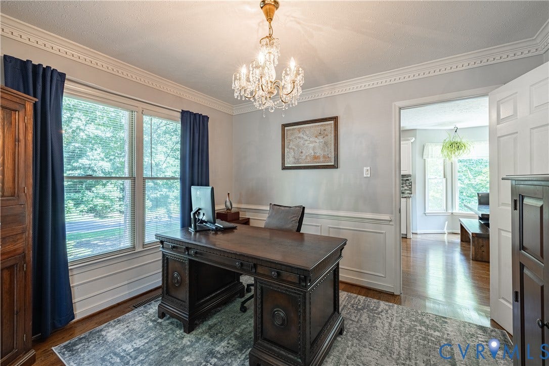Interior room featuring crown molding, hardwood flooring, and a crystal chandelier