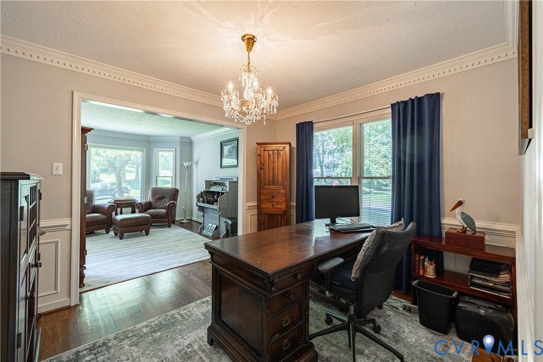 Interior space featuring an ornate chandelier, decorative crown molding, and wainscoting