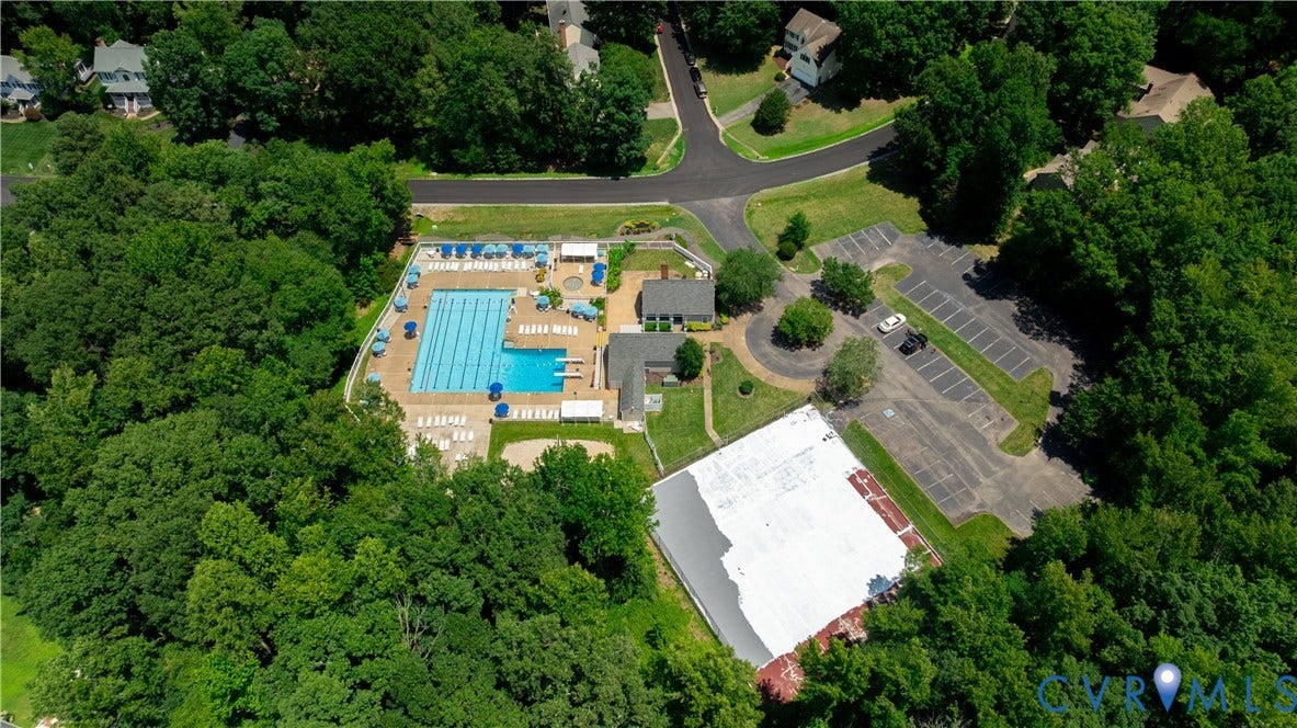 Community amenities featuring a large swimming pool with lane lines, a separate smaller pool, multiple lounge chairs, and blue umbrellas