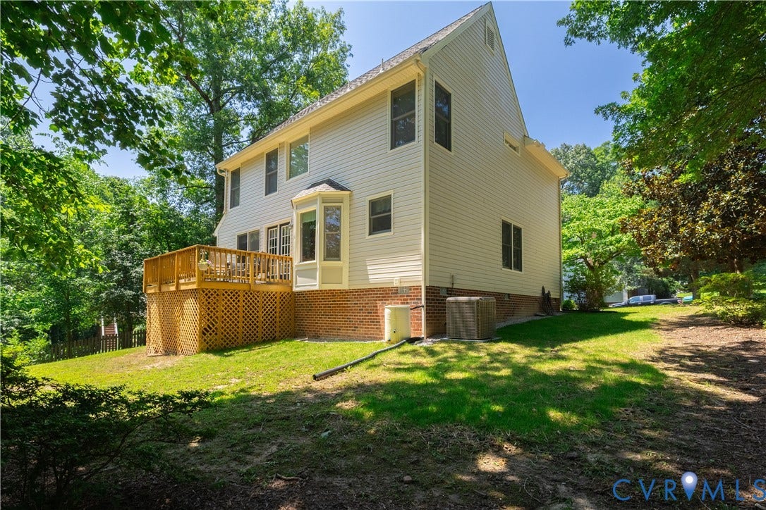 Rear exterior featuring a wooden deck with lattice skirting, bay window, and siding facade