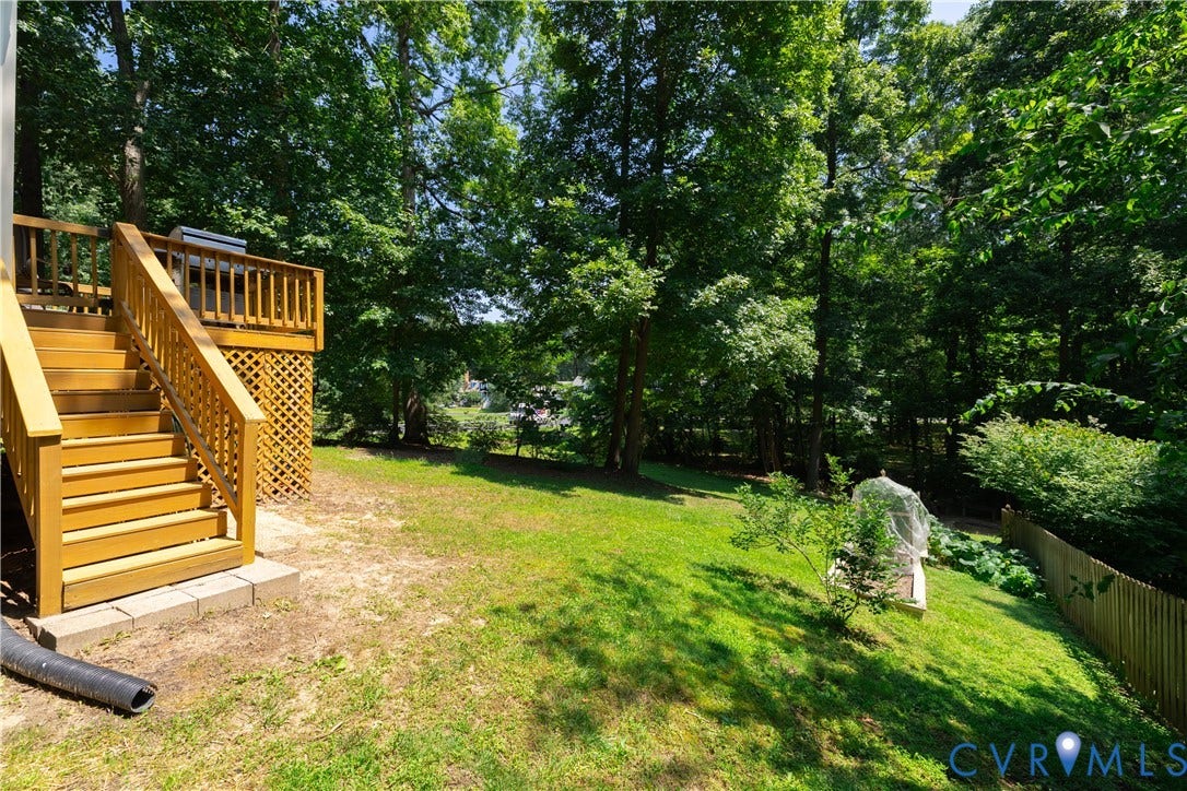 Elevated wood deck with lattice skirting, wood railings, and stairs descending to a sloped grassy yard