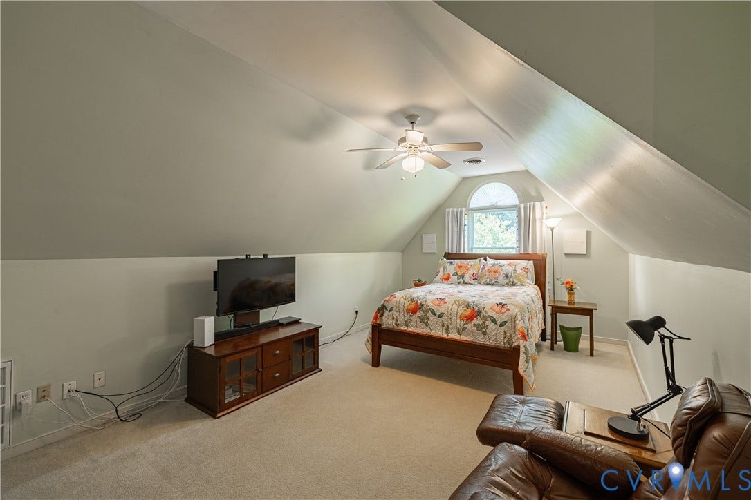 Carpeted room with sloped ceilings and a ceiling fan