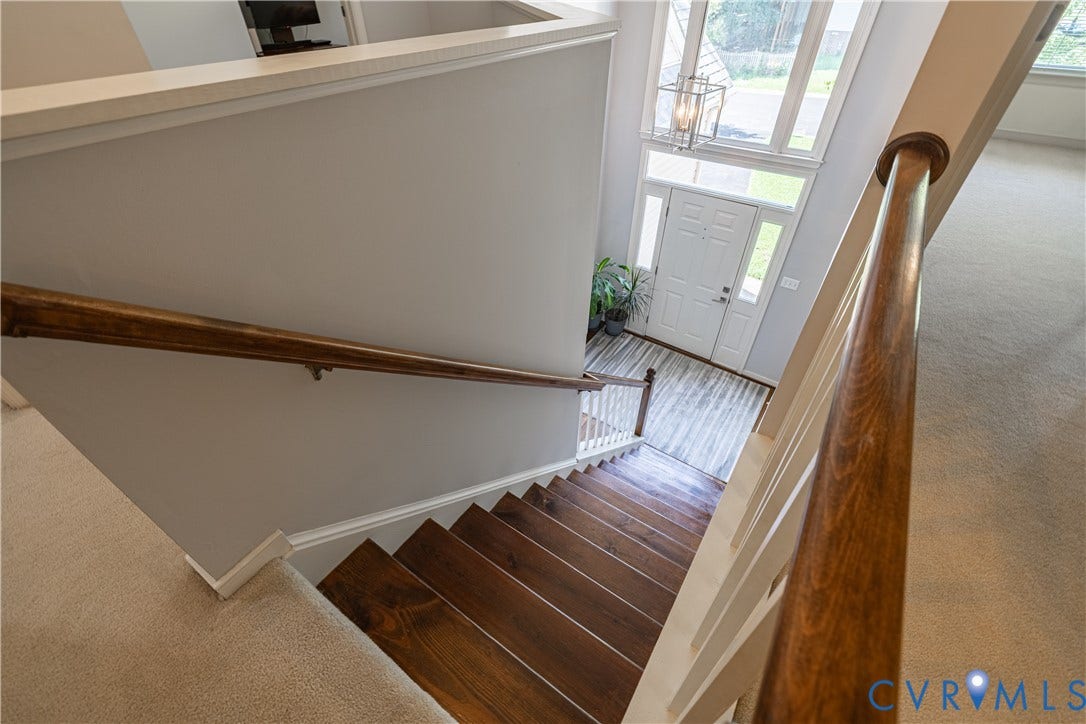 Two-story foyer featuring a white paneled entry door with sidelights, transom windows, a multi-pane window surround, and a suspended lantern light fixture