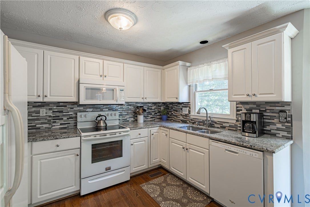Kitchen featuring white cabinetry, granite countertops, a mosaic tile backsplash, stainless steel sink with a gooseneck faucet, and wood-finish flooring