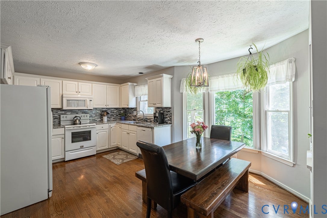 Kitchen with white cabinetry, granite countertops, and a tiled backsplash