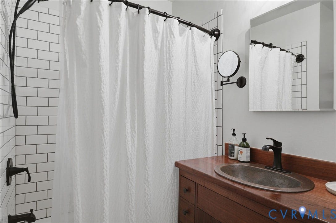 3332 Parkwood Avenue, Carytown, Richmond, VA 23221 Bathroom featuring subway tile shower surround, dark bronze shower fixtures, a wood vanity with integrated sink, and dark bronze sink faucet