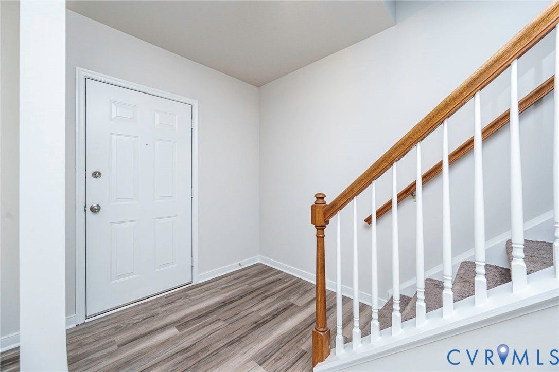2802 Goyne Terrace, Chester, VA 23831 Entryway featuring wood-finish flooring, a white paneled door, and a staircase with a wood handrail and white balusters