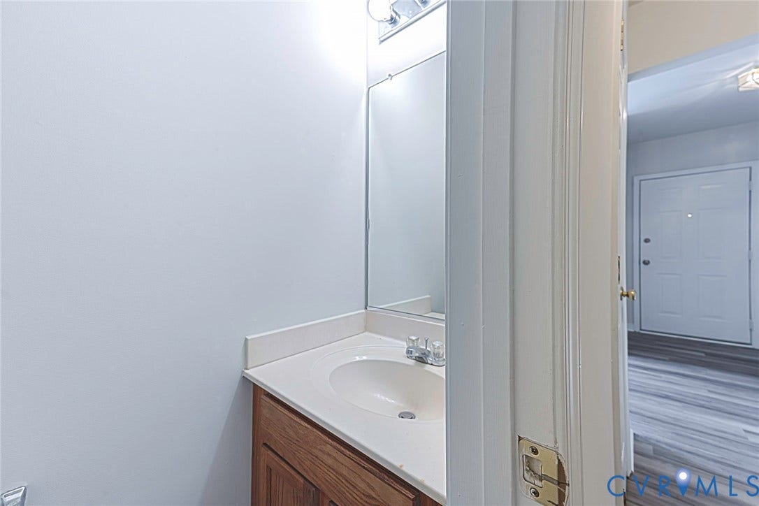 2802 Goyne Terrace, Chester, VA 23831 Vanity area featuring a wood-finish cabinet, integrated sink, light-toned countertop, and wall-mounted mirror