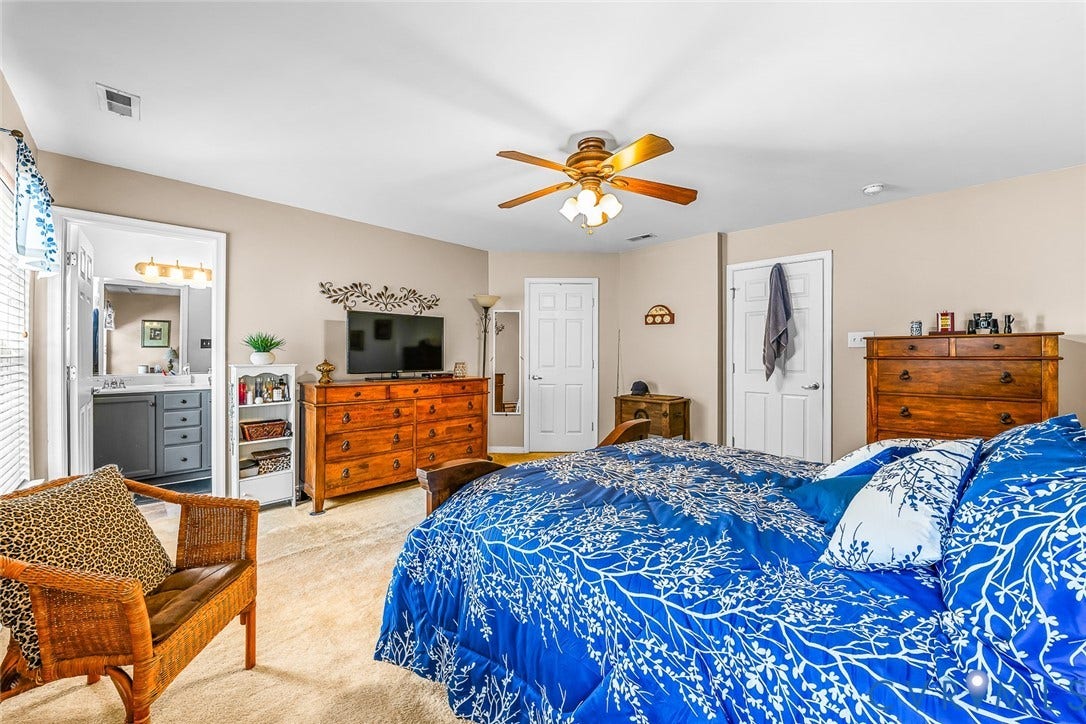 958 Wellston Court, Glen Allen, VA 23059 Carpeted bedroom featuring a ceiling fan with light fixture, neutral wall paint, and a visible doorway to a bathroom with a vanity and mirror