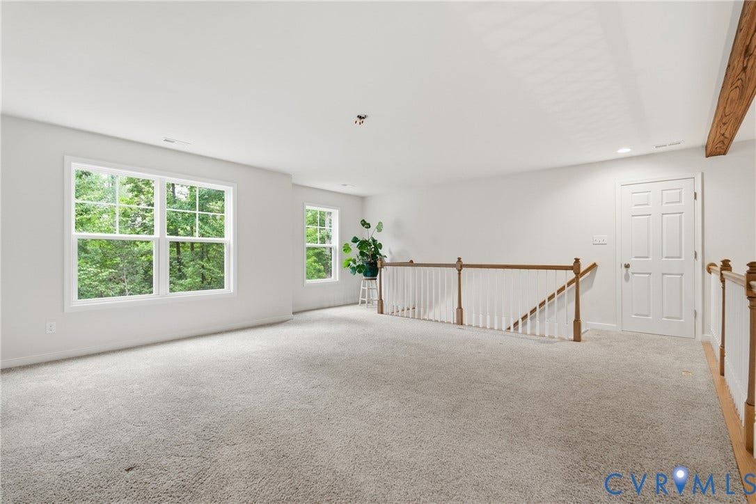 3780 Aston Trail, Powhatan, VA 23139 Expansive carpeted area with multiple windows, recessed lighting, a paneled door, and a wooden stair railing with white spindles