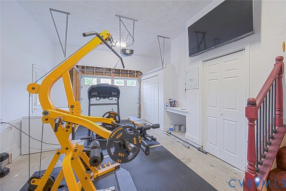 Finished garage space with multiple storage closets, a built-in shelf, and a staircase featuring a dark wood handrail with black iron balusters