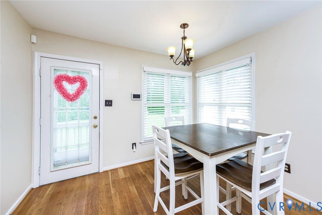 Dining area with wood-finish flooring, bay windows, and a glass-paneled door to the exterior
