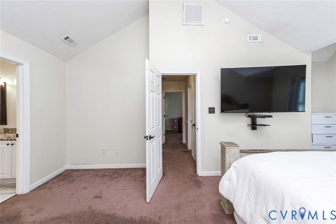 Vaulted ceiling bedroom featuring plush carpeting and neutral wall tones