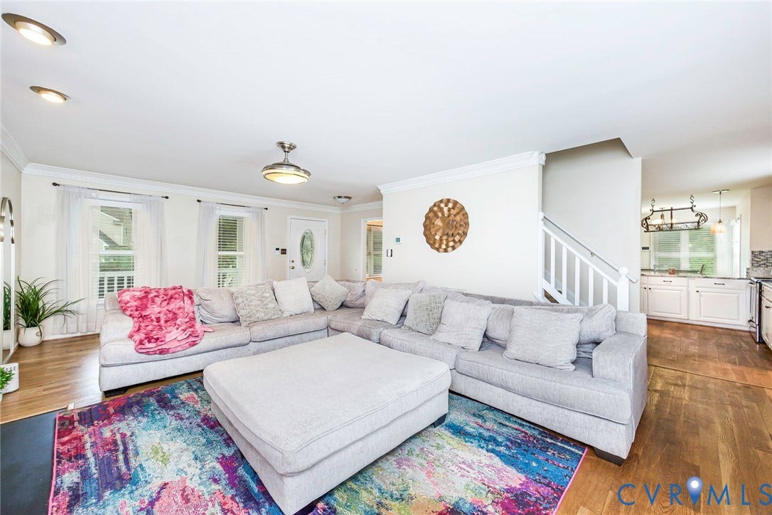 Open-concept living area featuring wood-finish flooring, recessed lighting, and crown molding