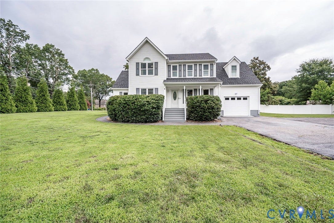 White two-story residence with a single-car garage and a paved driveway