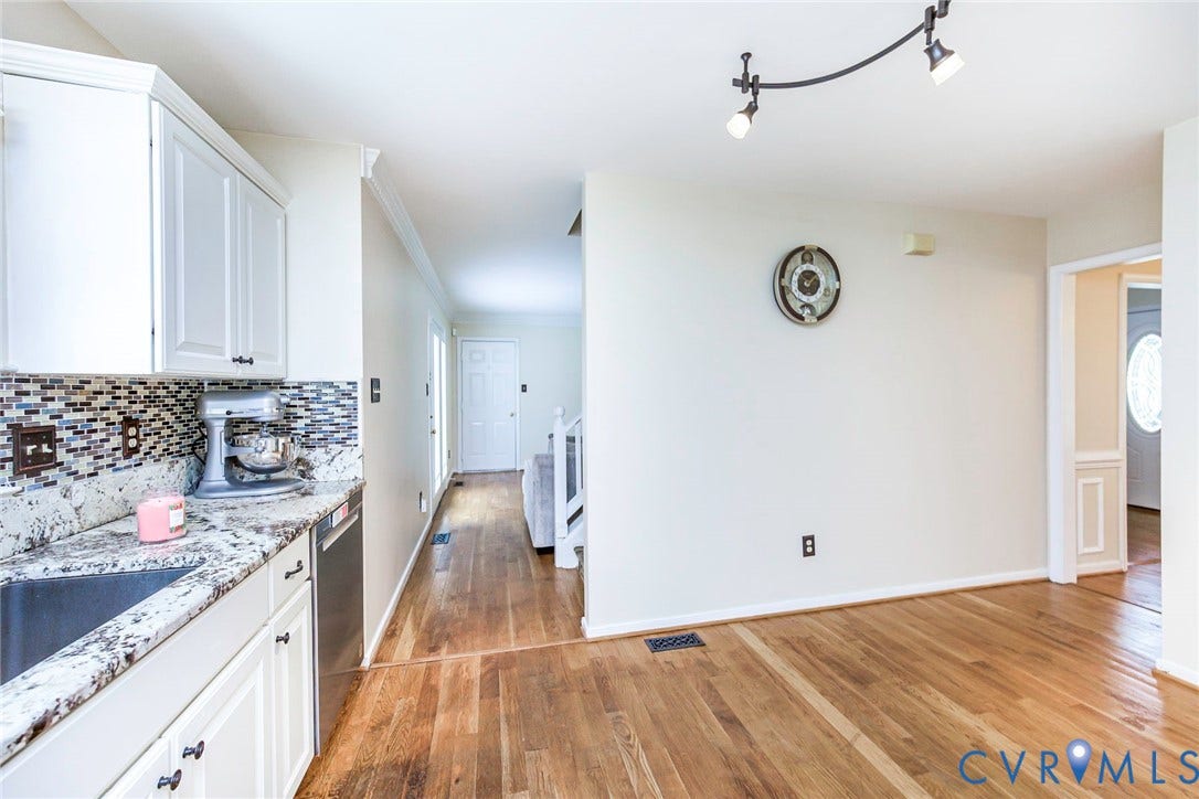 Kitchen area featuring white cabinetry, a mosaic tile backsplash, and a speckled countertop