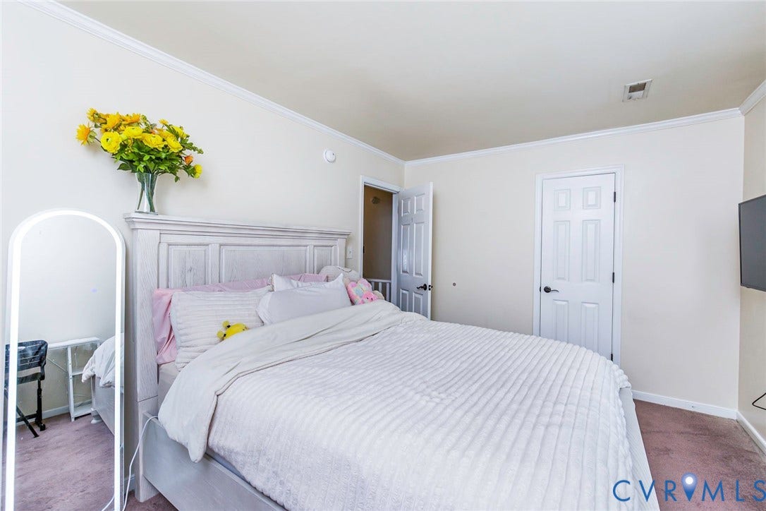 Neutral-toned bedroom featuring crown molding, panel doors with dark hardware, and wall-to-wall carpeting