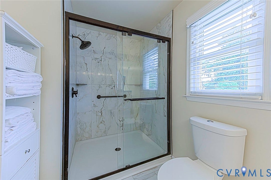 Walk-in shower with clear glass enclosure and dark bronze fixtures