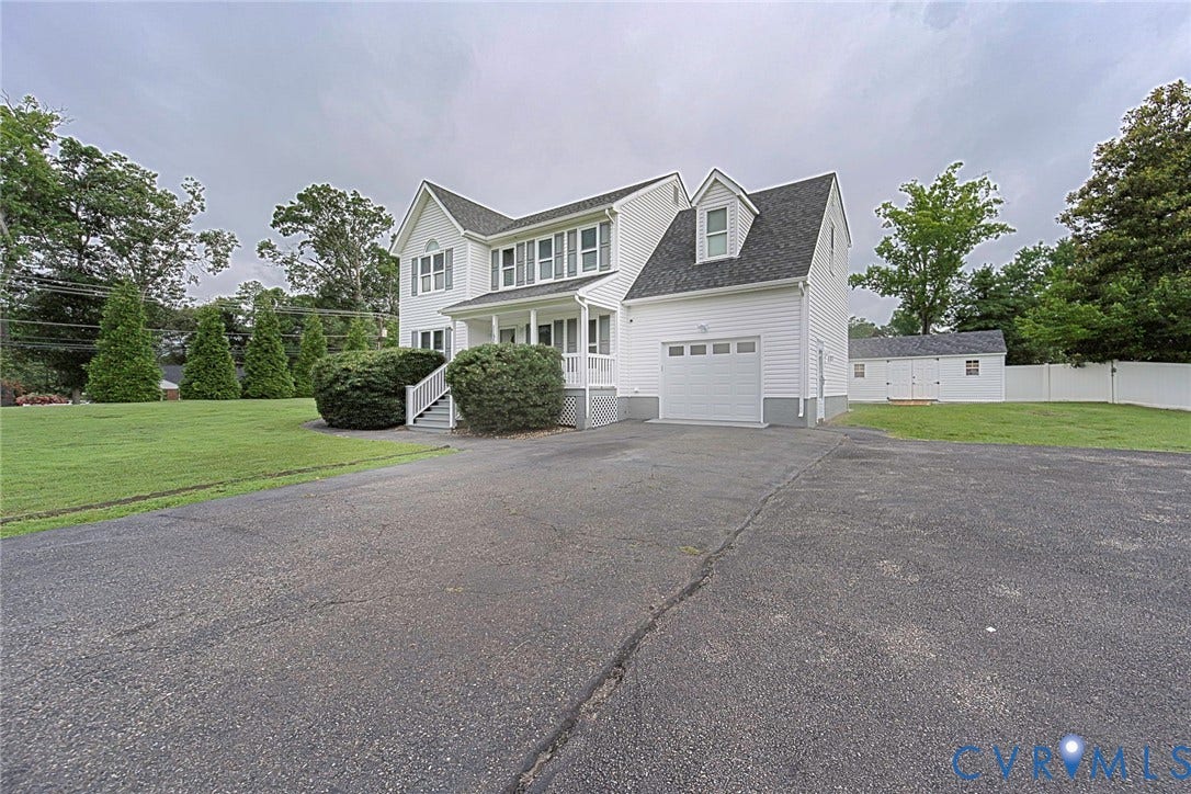 Colonial-style residence featuring white siding, a covered front porch, and an attached single-car garage