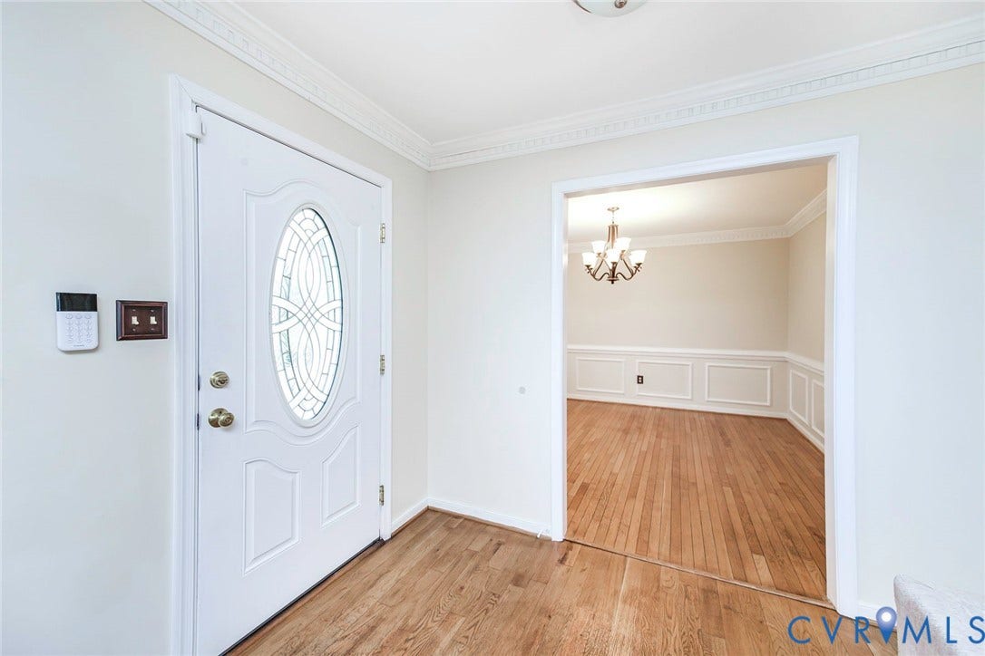 Entryway featuring a white door with an oval leaded glass insert, wood-finish flooring, and crown molding