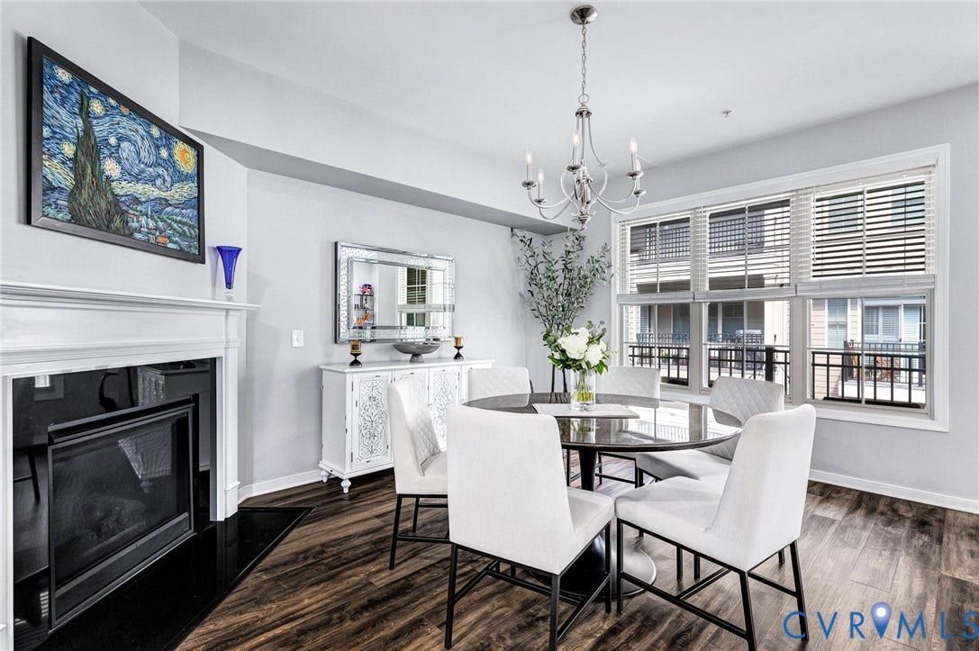 Dining area featuring wood-finish flooring, a white mantel fireplace with a black insert, and a white buffet cabinet below a framed mirror