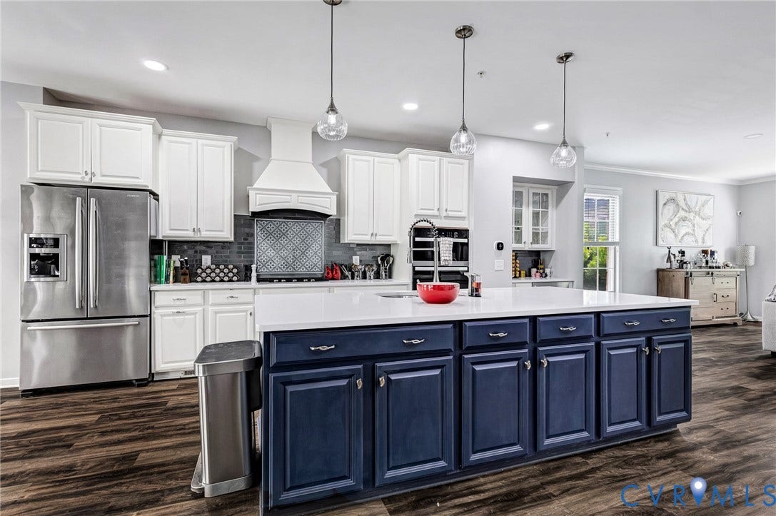 Spacious kitchen featuring an expansive center island with blue cabinetry, white countertops, and three pendant light fixtures