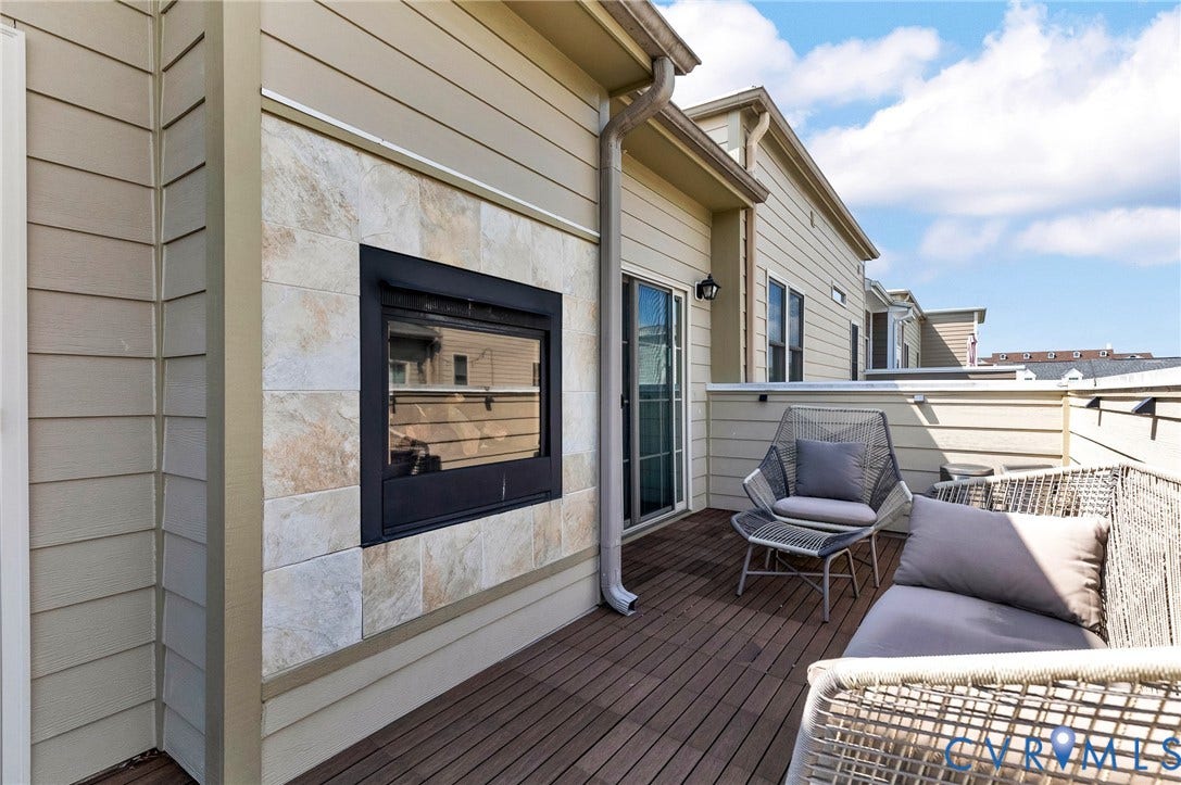 Outdoor deck featuring composite decking, an exterior fireplace with a stone surround, and horizontal siding