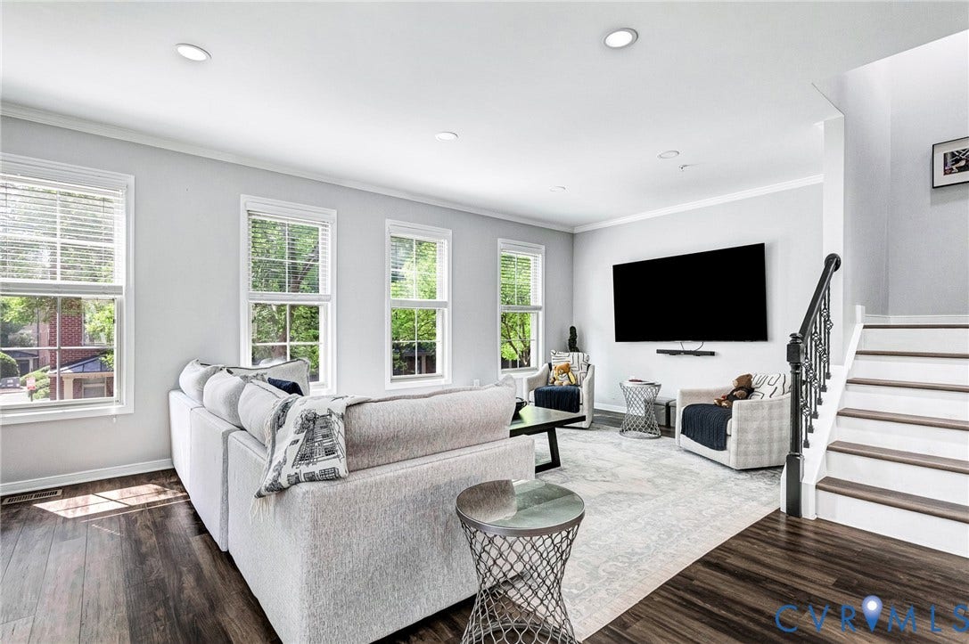 Living area featuring dark wood-finish flooring, recessed lighting, and multiple windows