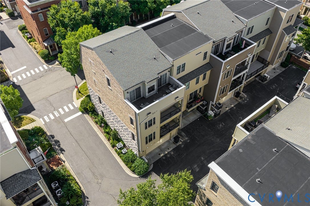 Modern multi-story residential building featuring a light-colored facade, multiple private balconies, a flat roof, and an integrated garage entrance