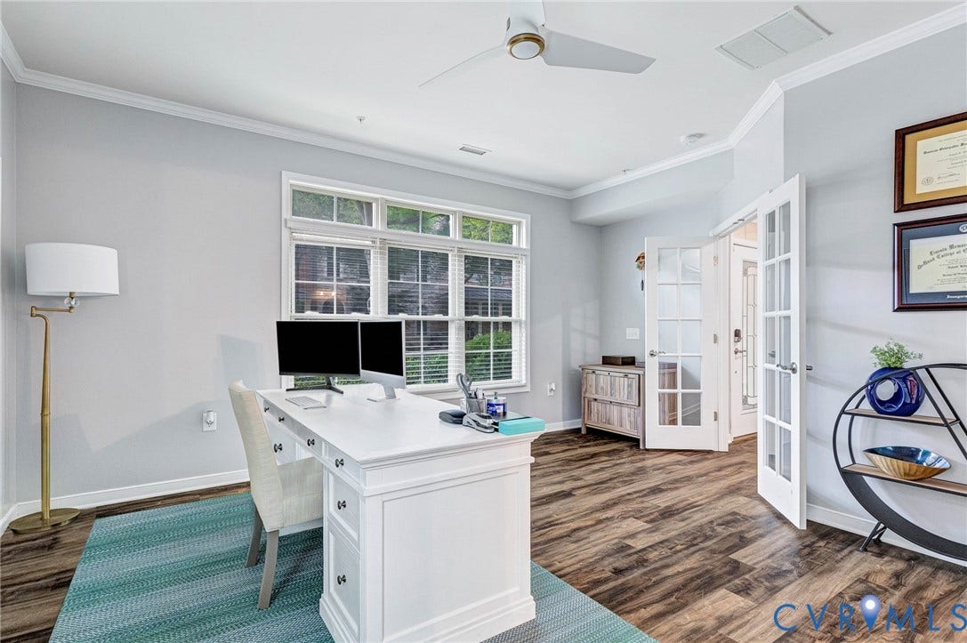 Light-filled room featuring wood-finish flooring, a multi-pane window, ceiling fan, and crown molding
