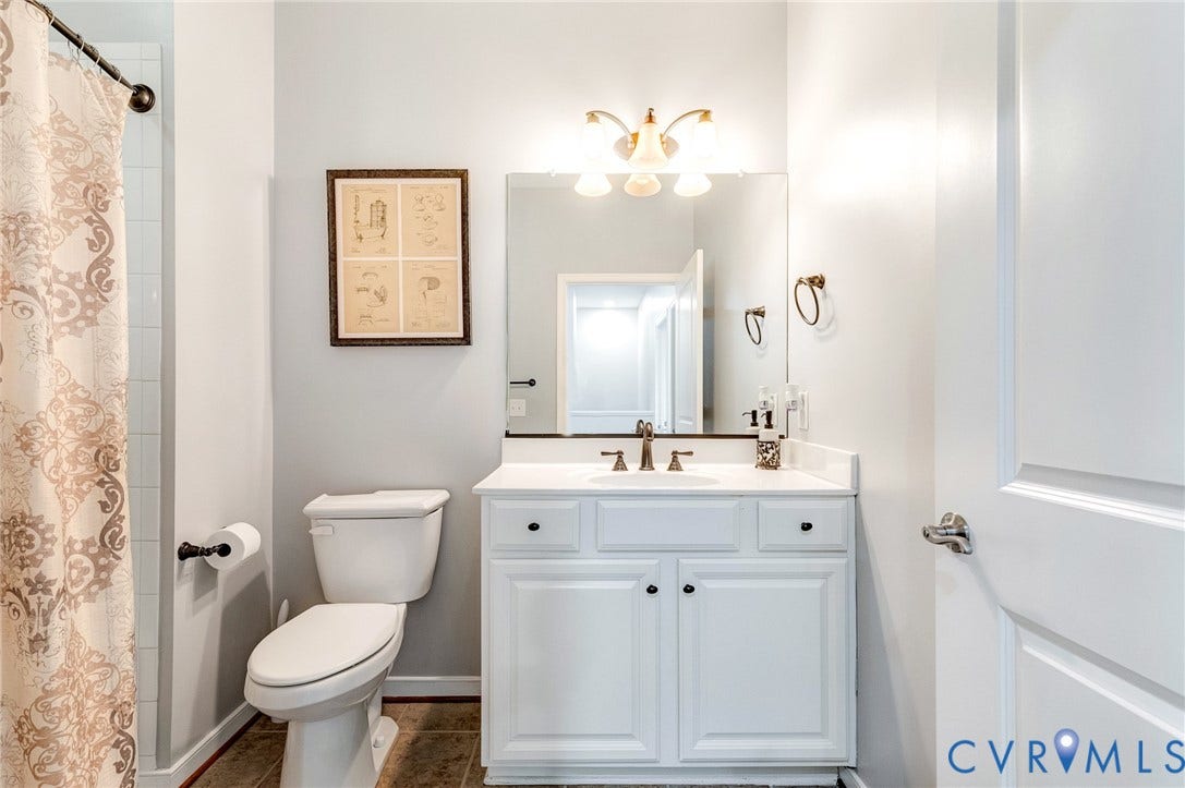 Bathroom featuring a white vanity with integrated sink, bronze-finish faucet, and coordinating cabinet pulls