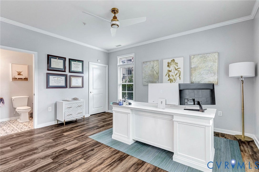 Dedicated office space featuring wood-finish flooring, light gray walls, and crown molding