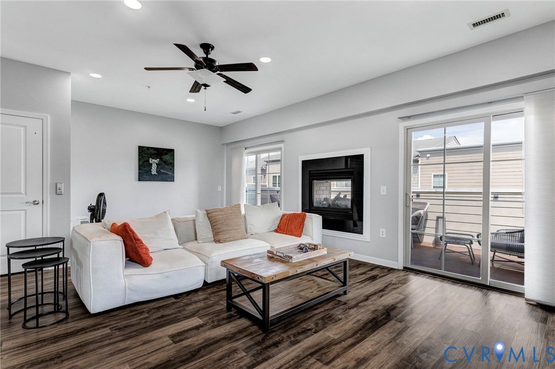 Spacious living area featuring wood-finish flooring, a contemporary fireplace, and a ceiling fan