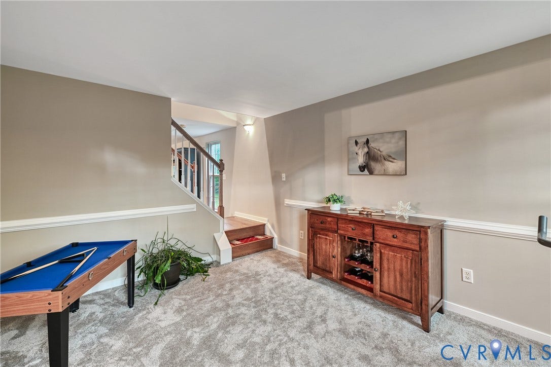 519 N Timber Tribe, Lake Anna, Mineral, VA 23117 Carpeted recreation area featuring neutral wall tones, white trim, and a staircase with wood-finish handrails and white balusters