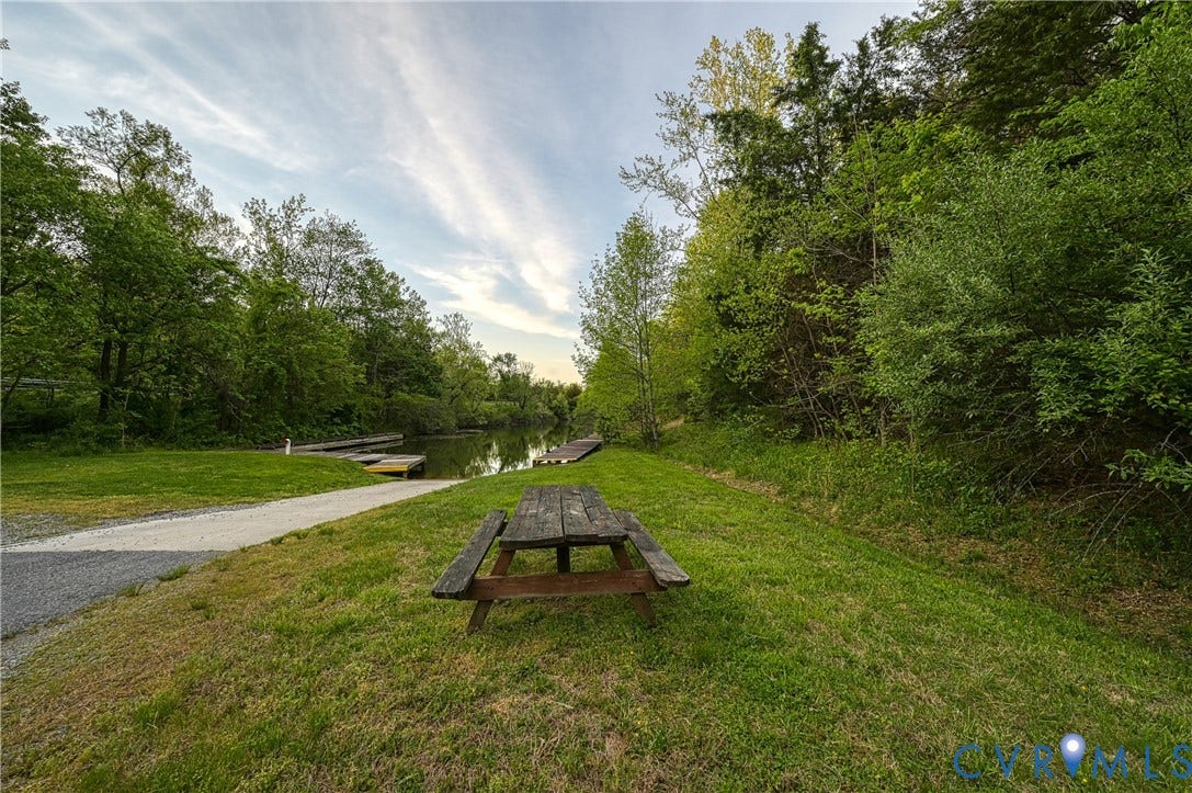 519 N Timber Tribe, Lake Anna, Mineral, VA 23117 Common area setting featuring a wooden picnic table, gravel pathway, mature trees, and a wooden dock structure