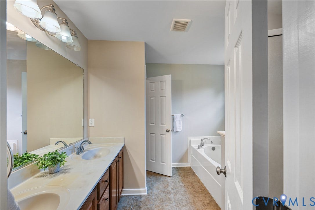 519 N Timber Tribe, Lake Anna, Mineral, VA 23117 Bathroom featuring a double vanity with integrated sinks, a large wall-mounted mirror, and a built-in bathtub with a shower