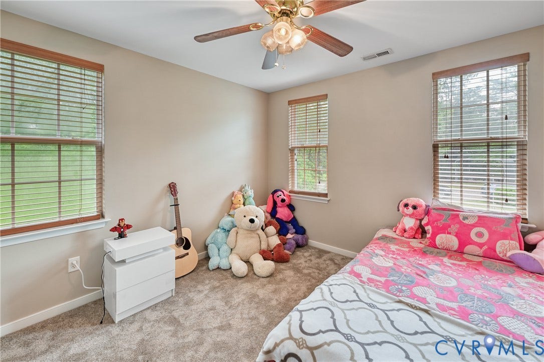 519 N Timber Tribe, Lake Anna, Mineral, VA 23117 Neutral wall paint complemented by two windows with wood-finish blinds, a ceiling fan with light fixture, and plush carpet flooring