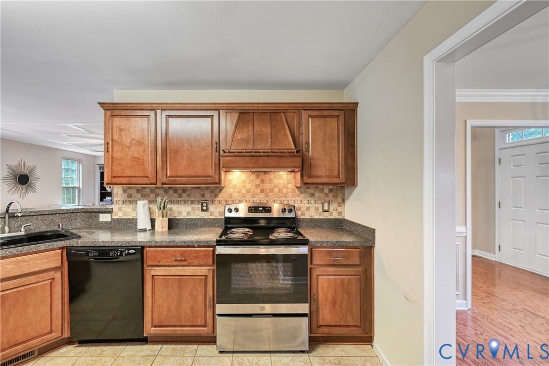 519 N Timber Tribe, Lake Anna, Mineral, VA 23117 Kitchen featuring wood-finish cabinetry, speckled countertops, and a tiled backsplash
