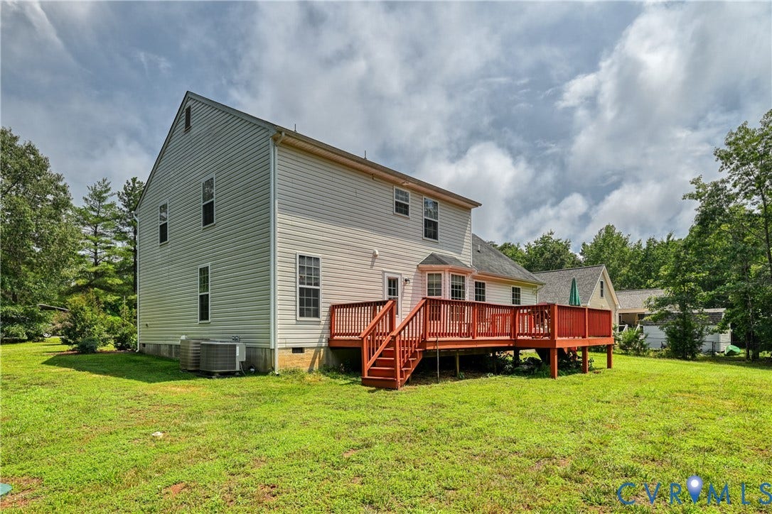 519 N Timber Tribe, Lake Anna, Mineral, VA 23117 Rear exterior featuring a spacious wooden deck with railings, vinyl siding, multiple windows, and an expansive lawn