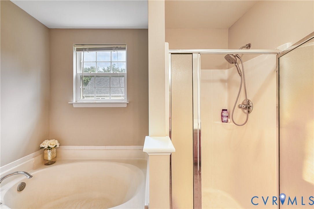 519 N Timber Tribe, Lake Anna, Mineral, VA 23117 Soaking tub with chrome fixtures and a large window, alongside a glass-enclosed shower with a handheld showerhead